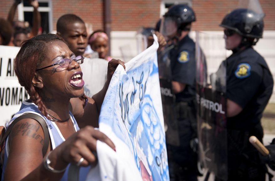 Marcelle Stewart, left, confronts police officers during a march and rally in downtown Ferguson, Mo. Monday, Aug. 11, 2014. The group marched along the closed street, rallying in front of the town's police headquarters to protest the shooting of 18-year-old Michael Brown by Ferguson police officers. Brown, who was killed in a confrontation with police in the St. Louis suburb, was shot Saturday, Aug. 9, 2014, and died following the confrontation with police. Stewart said she was attending the rally because her son-in-law Jason Moore died after being shot with a taser by police. (AP Photo/Sid Hastings)