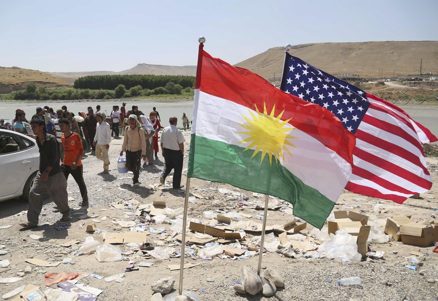 U.S. and Kurdish flags flutter in the wind while displaced Iraqis from the Yazidi community cross the Syria-Iraq border at Feeshkhabour bridge over the Tigris River at Feeshkhabour border point, in northern Iraq, Sunday, Aug. 10, 2014. Kurdish authorities at the border believe some 45,000 Yazidis passed the river crossing in the past week and thousands more are still stranded in the mountains. (AP Photo/ Khalid Mohammed)