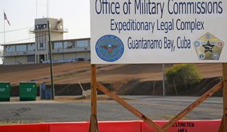 FILE - This June 17, 2013, file photo, shows a sign outside the Courthouse One Expeditionary Legal Complex at Naval Station Guantanamo Bay, Cuba. U.S. prosecutors are asking a military judge to reconsider his decision to try one of the men accused of plotting the Sept. 11 attack apart from the other four. Prosecutors have asked Army Col. James Pohl to hear arguments on their emergency motion involving Binalshibh first thing Monday, Aug. 11, 2014, at a pretrial hearing at the Guantanamo Bay naval base in Cuba. (AP Photo/Bill Gorman, File)