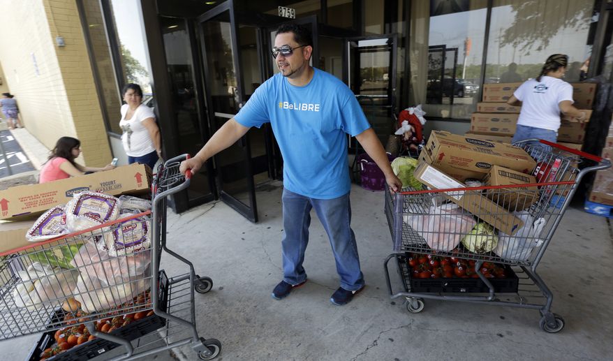 ** FILE ** In this July 3, 2014, photo, pastor Marcus Burgos, center, helps distribute groceries at a food bank at the Abundant Life Church in San Antonio. The food bank is cosponsored by the Libre Initiative, partly funded by conservative billionaires Charles and David Koch, which is looking to make inroads with the rising voting block of Hispanics. (AP Photo/Eric Gay)