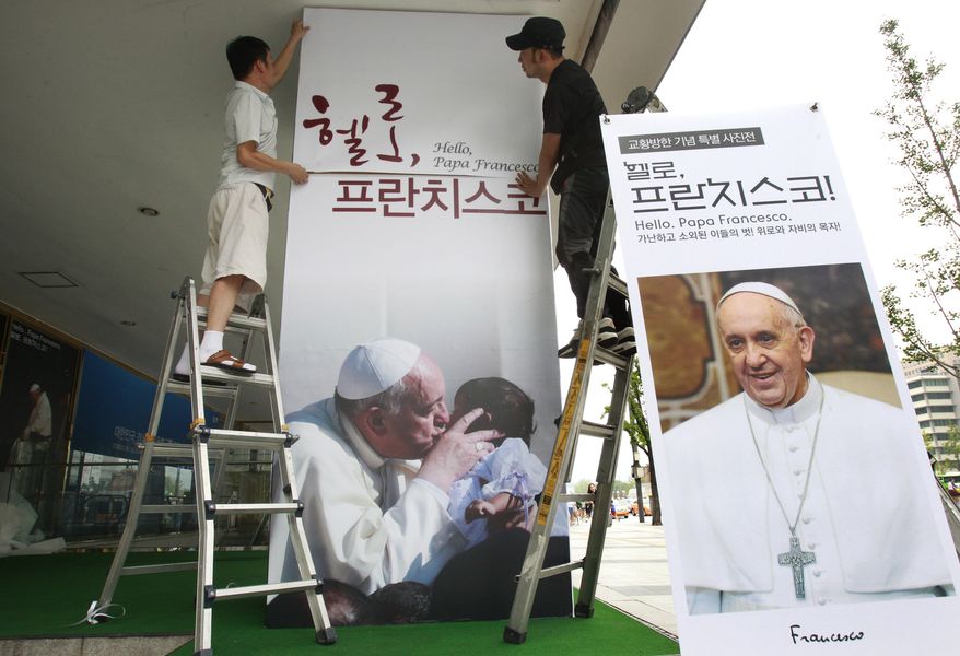 Workers set up a poster of Pope Francis' photo exhibition "Hello, Pope Francis!" at the Sejong Culture Center in Seoul, South Korea. The pope is scheduled to make a five-day trip to South Korea, starting Wednesday. (AP Photo/Ahn Young-joon)