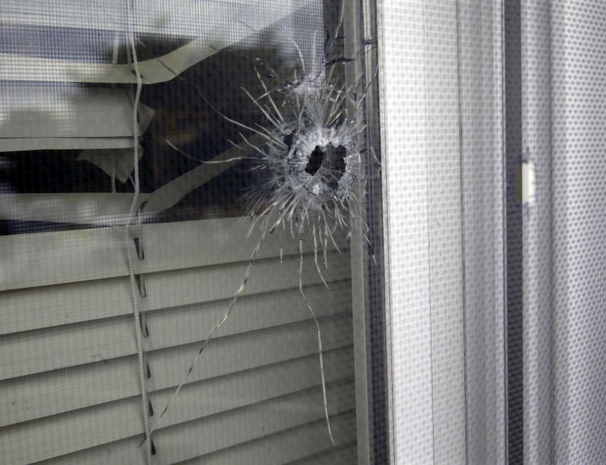A bullet hole is seen in a window at police headquarters Tuesday, Aug. 12, 2014, in West Deptford, N.J. An early morning drive-by shooting left the outside of the southern New Jersey police station riddled with bullets, but no officers were injured, authorities said Tuesday.  (AP Photo/Mel Evans)