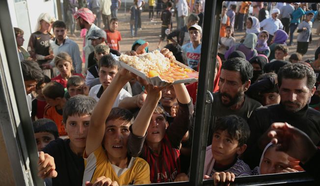 desperation: Displaced Yazidi Iraqis gather for food at the Nowruz camp in Derike, Syria. While the U.S. and Iraqi militaries have given food and water, the Kurds took it on themselves to rescue them, a sign of how Syria&#x27;s Kurds are using the conflict to establish their own rule. (Associated Press)