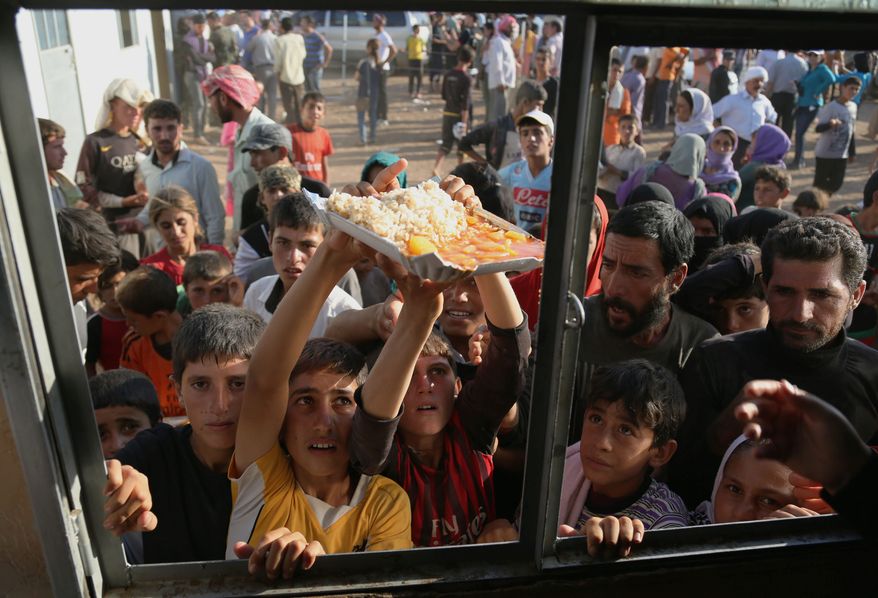 desperation: Displaced Yazidi Iraqis gather for food at the Nowruz camp in Derike, Syria. While the U.S. and Iraqi militaries have given food and water, the Kurds took it on themselves to rescue them, a sign of how Syria&#39;s Kurds are using the conflict to establish their own rule. (Associated Press)