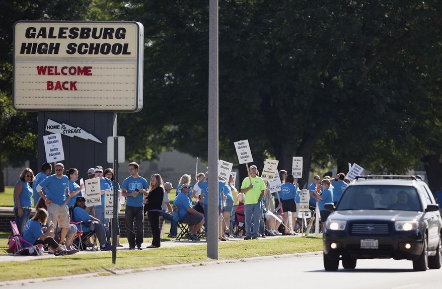 Teachers walk a picket line in front of Galesburg High School in Galesburg, Ill., Wednesday, Aug. 13, 2014, after the Galesburg Education Association turned down a contract offer late Tuesday from District 205 after more than 15 hours of mediation in the past two days. It's the first strike in Galesburg in 37 years. School is scheduled to start Thursday. (AP Photo/The Register-Mail, Steve Davis)