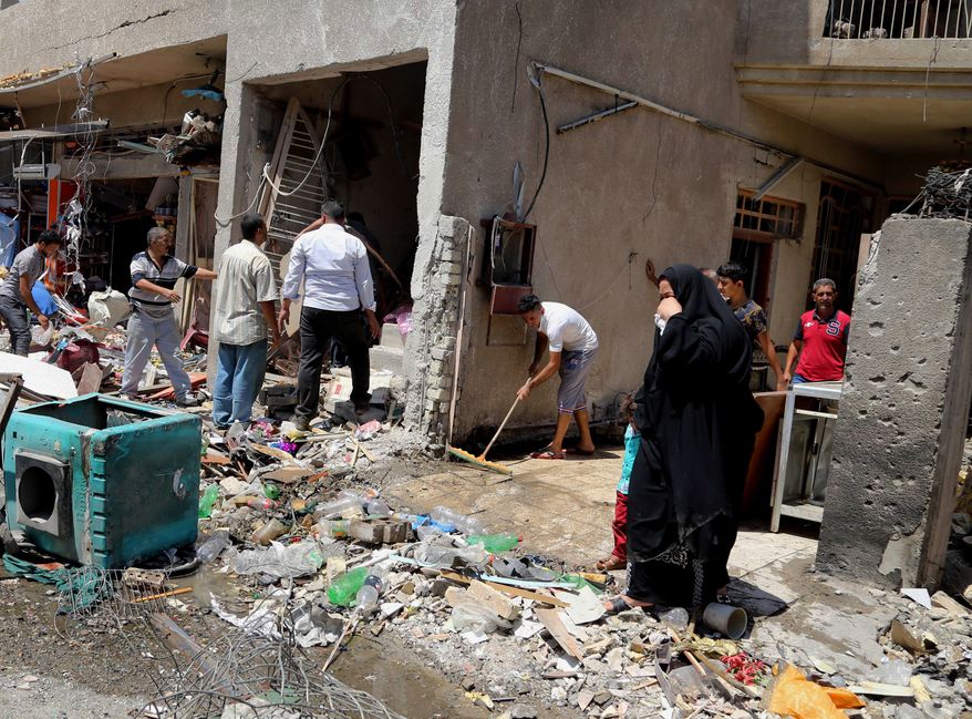 People inspect the site of a car bomb attack as others clear debris in Baghdad, Iraq, Wednesday, Aug. 13, 2014. A string of attacks in and around the capital killed more than a dozen and wounded dozens. (AP Photo/Karim Kadim)