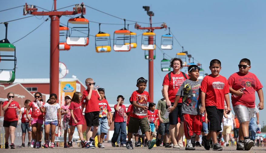 In this photo from Aug. 27, 2013, Howard Elementary students walk through the fairgrounds at the State Fair in Grand Island, Neb. The Nebraska State Fair's new home in Grand Island places it closer to the center of the state, but the move from Lincoln four years ago has created a potential opening for Iowa. Both fairs are advertising to Omaha residents, but organizers say they aren't competing. They argue that the fairs are scheduled at different times of the month, and offer different concerts and events. (AP Photo/The Grand Island Independent, Barrett Stinson)