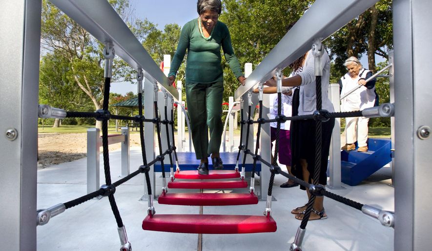 In this photo taken on Wednesday, Aug. 13, 2014, 84-year-old Zady Jones walks across a rope step bridge while trying out the new senior playground at Carbide Park in La Marque, Texas. The playground will be officially open to the public Thursday, after a ribbon-cutting ceremony. (AP Photo/The Galveston County Daily News, Stuart Villanueva) MANDATORY CREDIT, MAGS OUT, TV OUT