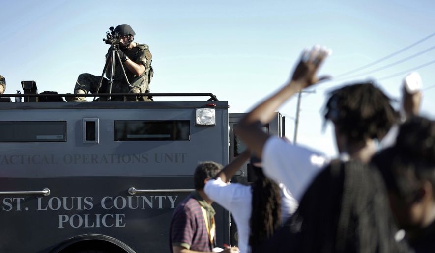 A member of the St. Louis County Police Department points his weapon in the direction of a group of protesters in Ferguson, Mo. on Wednesday, Aug. 13, 2014. On Saturday, Aug. 9, 2014, a white police officer fatally shot Michael Brown, an unarmed black teenager, in the St. Louis suburb. (AP Photo/Jeff Roberson)
