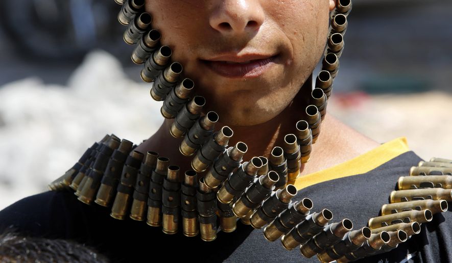 AP10ThingsToSee - A Palestinian youth wraps a bandolier of spent bullets leftover by the Israeli army, next to his destroyed home in Beit Hanoun, Gaza Strip, Monday, Aug. 11, 2014. (AP Photo/Hatem Moussa)