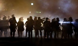 Police walk through a cloud of smoke as they clash with protesters Wednesday, Aug. 13, 2014, in Ferguson, Mo.  (AP Photo/Jeff Roberson)