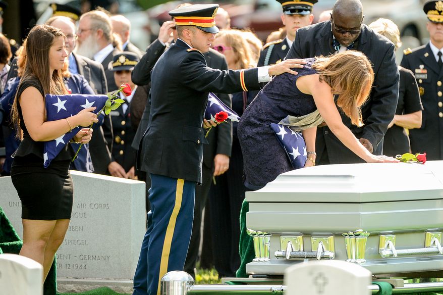 The children of Army Maj. Gen. Harold J. Greene, his daughter Amelia Greene, left, and his son Army 1st Lt. Matthew Greene, second from left, watches as Dr. Susan Myers, the wife of Army Maj. Gen. Harold J. Greene puts a rose on his coffin during his funeral service at Section 60 at Arlington National Cemetery, Arlington, Va., Thursday, August 14, 2014. Greene was killed in Afghanistan while at the national military academy in Kabul. He was the highest-ranking U.S. Army officer killed in combat since the Vietnam War. (Andrew Harnik/The Washington Times)