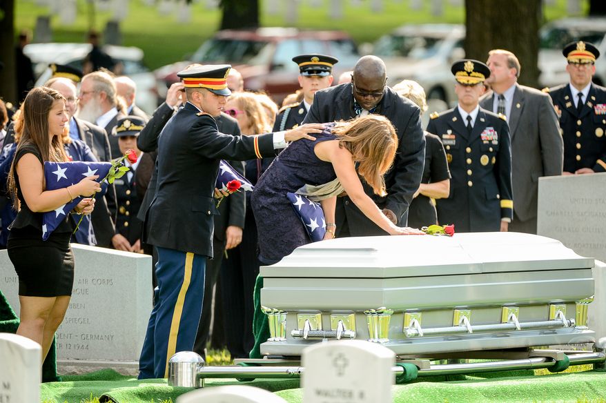 The children of Army Maj. Gen. Harold J. Greene, his daughter Amelia Greene, left, and his son Army 1st Lt. Matthew Greene, second from left, watches as Dr. Susan Myers, the wife of Army Maj. Gen. Harold J. Greene puts a rose on his coffin during his funeral service at Section 60 at Arlington National Cemetery, Arlington, Va., Thursday, August 14, 2014. Greene was killed in Afghanistan while at the national military academy in Kabul. He was the highest-ranking U.S. Army officer killed in combat since the Vietnam War. (Andrew Harnik/The Washington Times)
