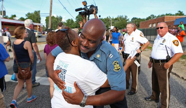 Capt. Ronald Johnson of the Missouri Highway Patrol hugs Angela Whitman, of Berkeley, Mo., on West Florissant Avenue in Ferguson, Mo., on Thursday, Aug. 14, 2014. The Missouri Highway Patrol seized control of the St. Louis suburb Thursday, stripping local police of their law-enforcement authority after four days of clashes between officers in riot gear and furious crowds protesting the death of an unarmed black teen shot by an officer. (AP Photo/St. Louis Post-Dispatch, David Carson)