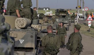 Russian solders with their several military vehicle gather at the rail road crossing about 30 kilometers (19 miles) from Ukrainian border at  Rostov-on-Don region, Russia, early Friday, Aug. 15, 2014. (AP Photo/Pavel Golovkin)