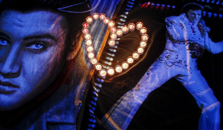Candles placed in a heart shape rest on Elvis blankets outside the gates of Graceland during a candlelight vigil in remembrance of Elvis’ death 37 years-ago, Friday, Aug. 15, 2014, in Memphis, Tenn. (AP Photo/The Commercial Appeal, Mark Weber)