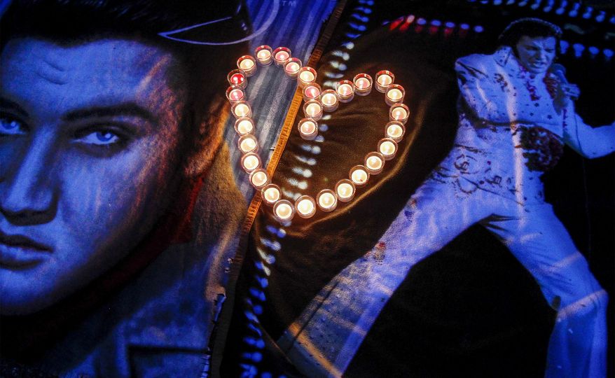 Candles placed in a heart shape rest on Elvis blankets outside the gates of Graceland during a candlelight vigil in remembrance of Elvis’ death 37 years-ago, Friday, Aug. 15, 2014, in Memphis, Tenn. (AP Photo/The Commercial Appeal, Mark Weber)