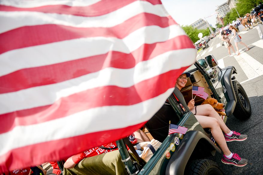 Retired Army Military Intelligence Officer Angelee Andoe of Lorton, Va., sits with her service dog, Franklin Delano Roosevelt, a golden retriever as they get ready to march with a group of Hero Dogs in the National Memorial Day Parade along Constitution Ave., Washington, D.C., Monday, May 26, 2014. Andoe, who suffers from PTSD, is helped by F.D.R. who is given to her by Hero Dogs, a non-profit which helps provide improved quality of life to Veterans with disabilities by raising, training, and placing service dogs with Veterans who have served honorably in the United States Armed Services. (Andrew Harnik/The Washington Times)