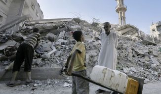 A Palestinian man talks to a boy carrying containers as they stand amid the rubble of al-Qassam mosque, hit by an Israeli airstrike. Hamas officials said they were holding out in hopes of getting more concessions in the curretn Egyptian-mediated talks. (AP Photo/Adel Hana)