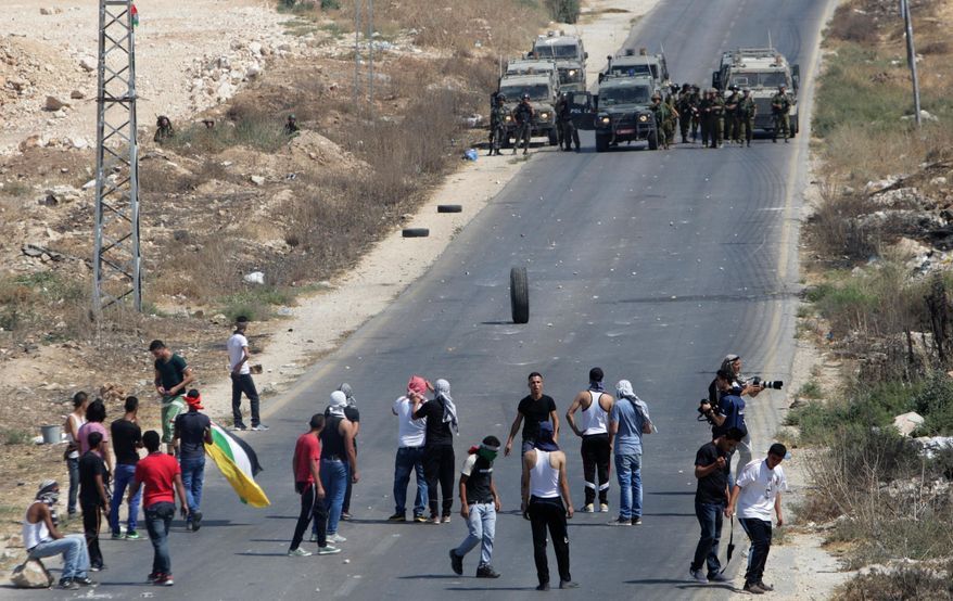 Palestinian protesters face Israeli soldiers, following a demonstration to support people in Gaza and Palestinian negotiators in Cairo, Egypt, during clashes near the West Bank city of Nablus on Friday, Aug. 15, 2014. Israel and Hamas are observing a five-day cease-fire which began at midnight Wednesday, in an attempt to allow talks between the sides in Cairo to continue. The negotiations are meant to secure a substantive end to the monthlong war and draw up a roadmap for the coastal territory of Gaza, which has been hard-hit in the fighting. (AP Photo/Nasser Ishtayeh)
