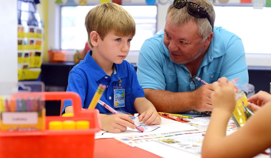 Grayson Murphy, 5, of Pink Hill, N.C., left, listens to his father Hal, right, as he settles into kindergarten on the first day of school Monday, Aug. 18, 2014, at Arendell Parrott Academy in Kinston, N.C. (AP Photo/Daily Free Press, Janet S. Carter)