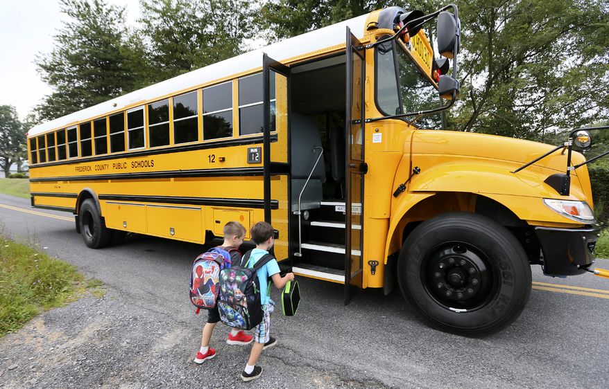 Cash Keeler 5, left and Riley Myers 5 board their bus to take them to their 1st day of kindergarten at Gainesboro Elementary School near Winchester, Va. on Monday, Aug. 18, 2014. Monday was the first day students reported to Frederick County, Va. Public Schools for the 2014-2015 year. (AP Photo/The Winchester Star, Ginger Perry)