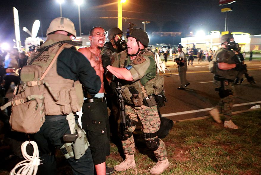 A protestor is detained Monday, Aug. 18, 2014, in Ferguson, Mo. The Aug. 9 shooting of Michael Brown by police has touched off rancorous protests in Ferguson, a St. Louis suburb where police have used riot gear and tear gas. (AP Photo/St. Louis Post-Dispatch, Christian Gooden) 