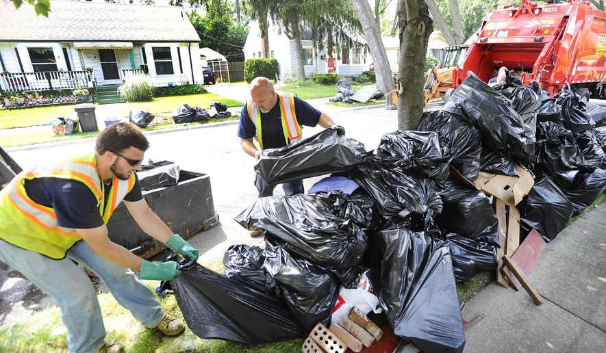 From left, Berkley DPS workers Tom Benaglio and Rod Halas help out Tringali, the Berkley waste and refuge contractor, collect the ever growing piles piles of water-damaged belongings from the curbside of Cambridge in Berkley Tuesday, Aug. 19, 2014. Trash collectors are overwhelmed by the amount of rain and sewage soaked waste people have removed from their basements in the wake of last week's floods in Metro Detroit. (Daniel Mears/ The Detroit News) Detroit News) (AP Photo/Detroit News, David Mears) DETROIT FREE PRESS OUT; HUFFINGTON POST OUT