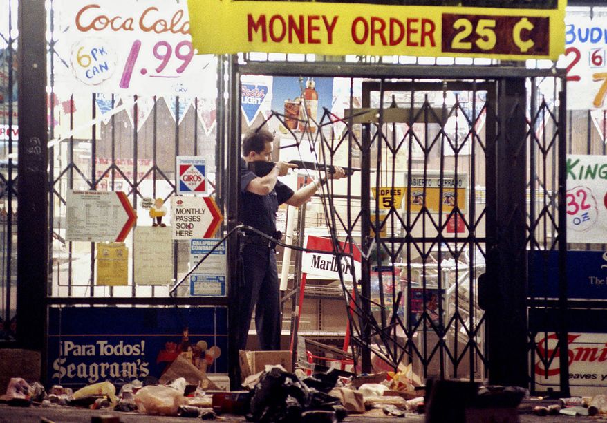 FILE - In this April 30, 1992 file photo, a Los Angeles police officer takes aim at a looter in a market at Alvarado and Beverly Boulevard in Los Angeles during the second night of rioting in the city. Rodney King, the black motorist whose 1991 videotaped beating by Los Angeles police officers was the touchstone for one of the most destructive race riots in the nation&#39;s history, has died, his publicist said Sunday, June 17, 2012. He was 47.(AP Photo/John Gaps III, File)