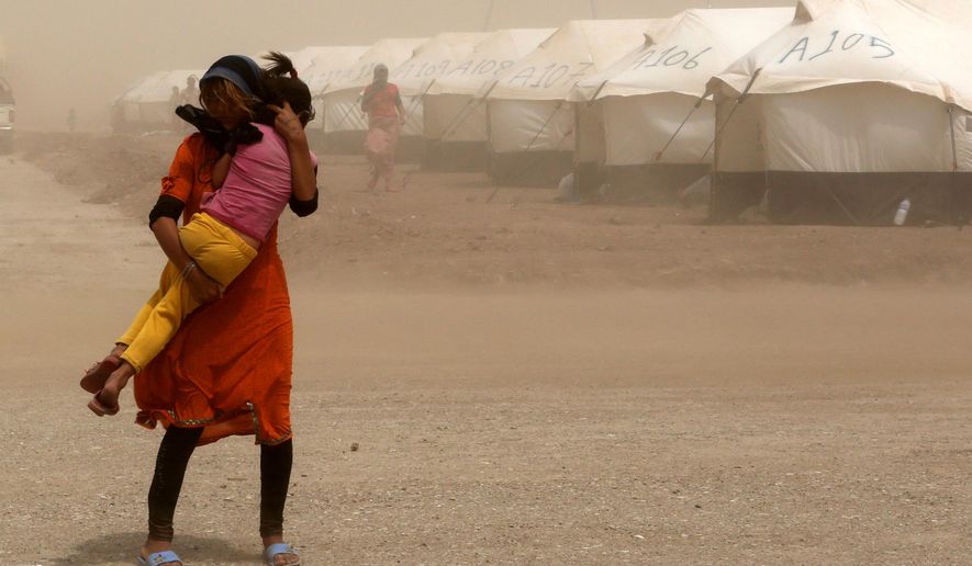 An internally displaced Iraqi woman holds her sister during a sandstorm at a new camp outside the Bajid Kandala camp in Feeshkhabour town, Iraq, Tuesday, Aug. 19, 2014. Some 1.5 million people have been displaced by fighting in Iraq since the Islamic State's rapid advance began in June, and thousands more have died. The scale of the humanitarian crisis prompted the U.N. to declare its highest level of emergency last week. (AP Photo/ Khalid Mohammed)