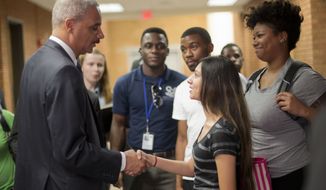 Attorney General Eric Holder shakes hands with Bri Ehsan, 25, right, following his meeting with students at St. Louis Community College Florissant Valley in Ferguson, Mo., Wednesday, Aug. 20, 2014. Holder arrived in Missouri on Wednesday, a small group of protesters gathered outside the building where a grand jury could begin hearing evidence to determine whether a Ferguson police officer who shot 18-year-old Michael Brown should be charged in his death.  (AP Photo/Pablo Martinez Monsivais/Pool)