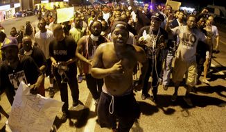 People march Tuesday, Aug. 19, 2014, during a rally for Michael Brown, who was killed by police Aug. 9 in Ferguson, Mo. (AP Photo/Charlie Riedel)