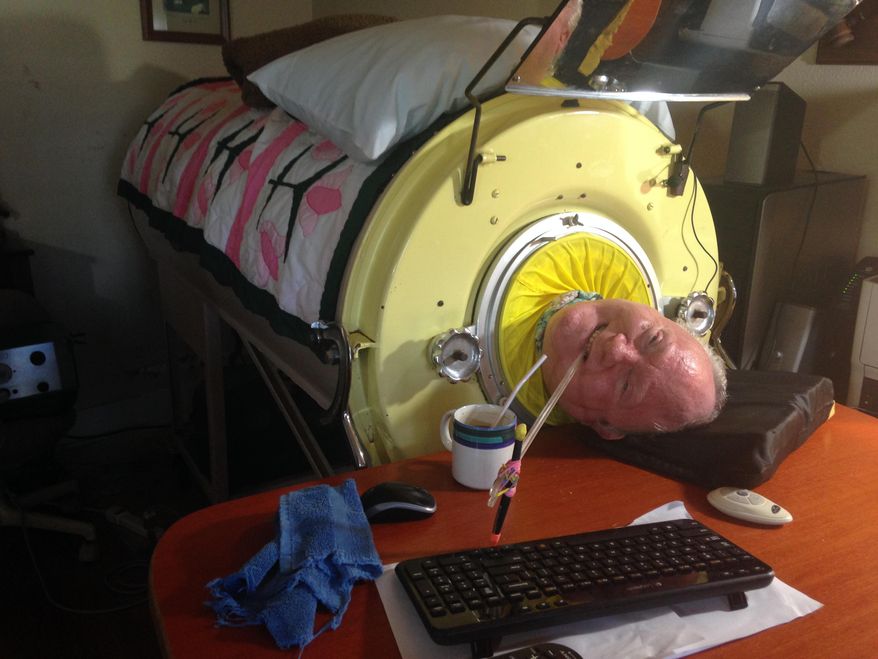 In this Aug. 9, 2014 photo, Paul Alexander uses a plastic stick with a pencil tied to it to type on a keyboard using only his mouth while in his iron lung at his home in Dallas. Alexander is one of 10 people left in the world who still uses an iron lung to breathe. (AP Photo/Courtesy Shelly Conlon, The Waxahachie Daily Light)