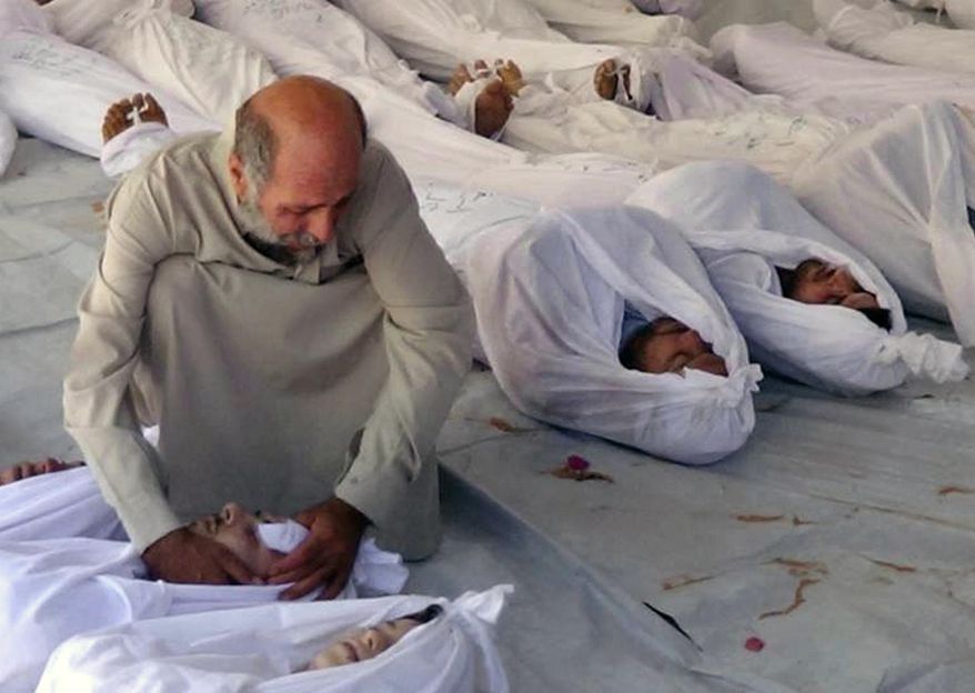FILE - This Aug. 21, 2013, citizen journalism image provided by the Media Office Of Douma City which has been authenticated based on its contents and other AP reporting, shows a Syrian man mourning over a dead body after an alleged poisonous gas attack fired by regime forces, according to activists, in Douma town, Damascus, Syria. An international human rights group says on the anniversary of the deadly chemical attack outside Damascus that “justice remains elusive” for the victims and their families. (AP Photo/Media Office Of Douma City, File)