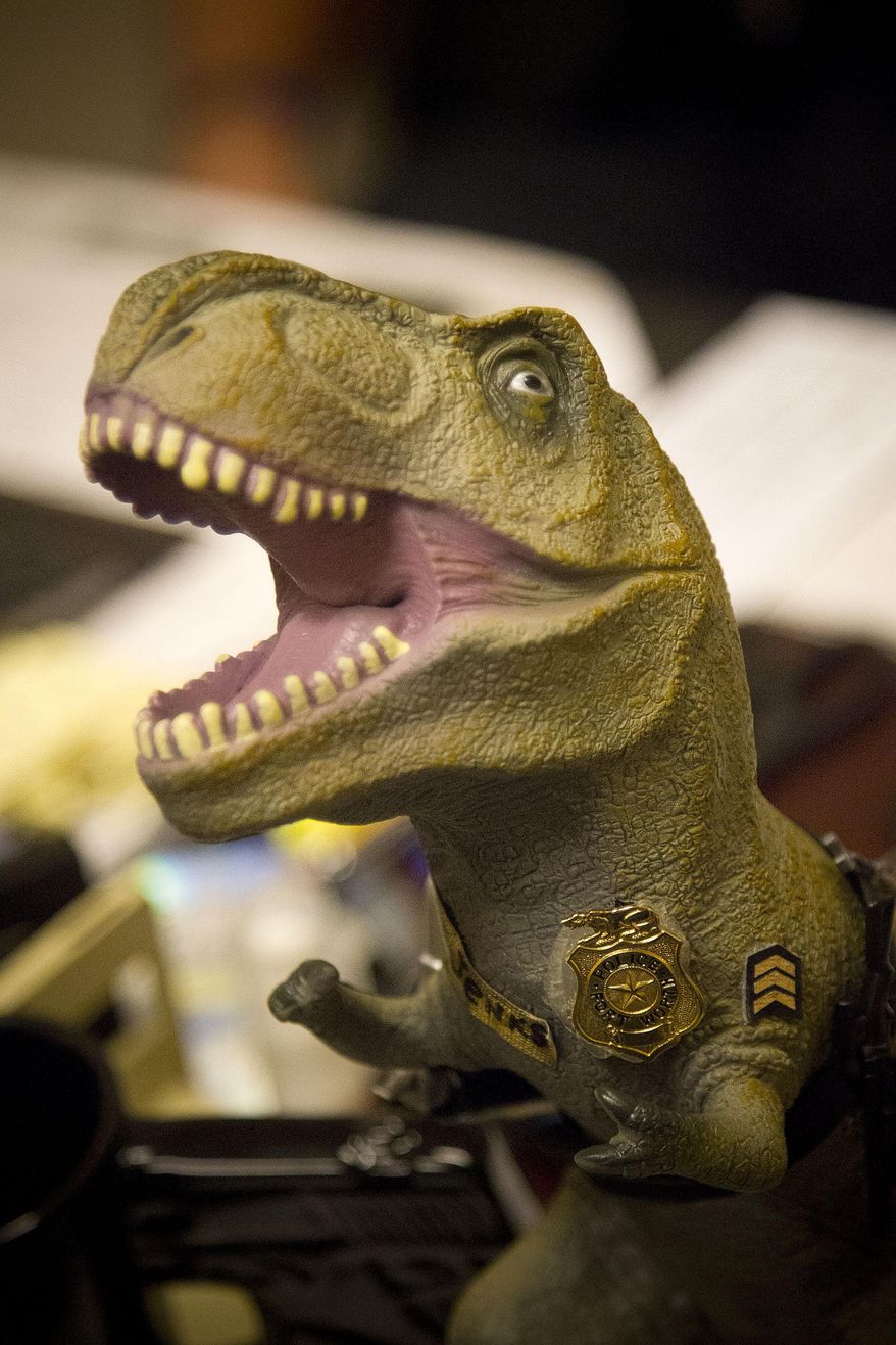 ADVANCE FOR MONDAY AUG. 25 -This July 30, 2014 photo shows a toy dinosaur that Sgt. Scott Jenkins, carries in Fort Worth, Texas. Jenkins decided to embrace the concept and now carries a toy dinosaur, complete with badge and gun wherever he goes. The dinosaur even has his own Facebook page. Jenkins is retiring in early September. (AP Photo/The Fort Worth Star-Telegram, Rodger Mallison) MAGS OUT; (FORT WORTH WEEKLY, 360 WEST); INTERNET OUT