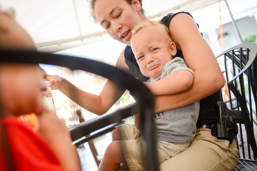Naomi Leydig of Sterling, Va. and her two sons Jaden and Jeremy, 3, left, eat dinner with her gun at The Cajun Experience during Second Amendment Wednesdays where patrons are allowed to open carry their guns, Leesburg, Va., Wednesday, August 20, 2014. (Andrew Harnik/The Washington Times)