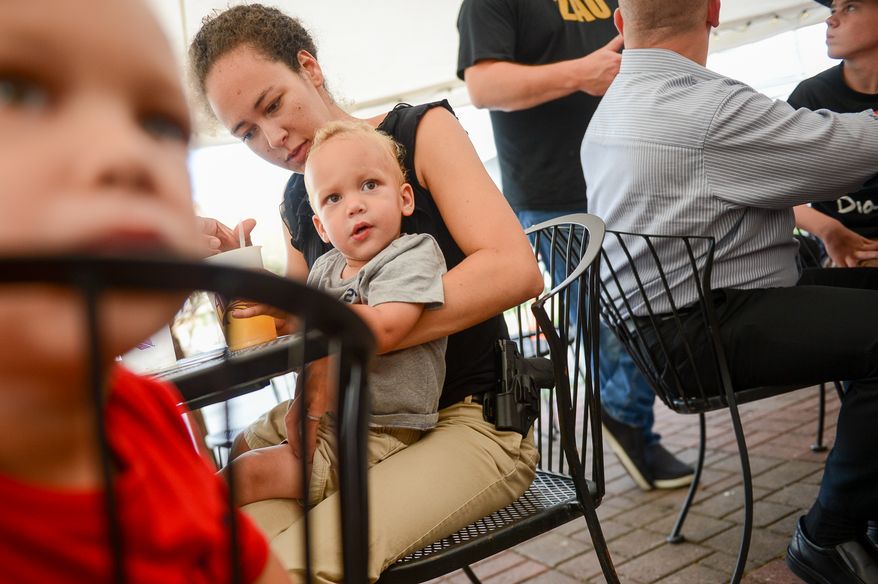 Naomi Leydig of Sterling, Va. and her two sons Jaden and Jeremy, 3, left, eat dinner with her gun at The Cajun Experience during Second Amendment Wednesdays where patrons are allowed to open carry their guns, Leesburg, Va., Wednesday, August 20, 2014. (Andrew Harnik/The Washington Times)