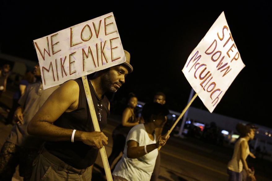 Protesters march Thursday, Aug. 21, 2014, in Ferguson, Mo. Protesters again gathered Thursday evening, walking in laps near the spot where Michael Brown was shot. Some were in organized groups, such as clergy members. More signs reflected calls by protesters to remove the prosecutor, Robert McCulloch, from the case. (AP Photo/Jeff Roberson)