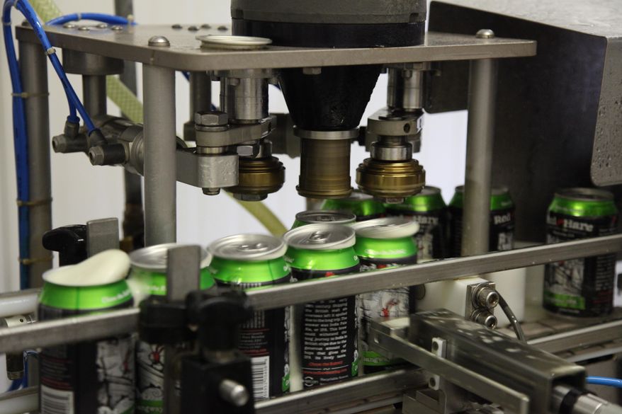 In this July 22, 2104 photo, Red Hare Brewing Company beer cans enter the lid securing stage of canning at the microbrewery's canning facility in Marietta, Ga. The Atlanta-based aluminum manufacturer Novelis Inc. has teamed up with the Marietta, Ga. microbrewery to introduce the first certified recycled beer can with not less than 90 percent recycled content. (AP Photo/Johnny Clark)