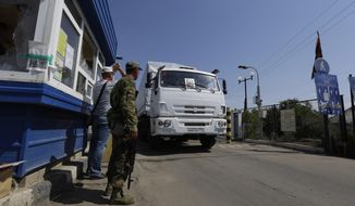 Ukrainian border guards look at the first aid truck as it passes the border post at Izvaryne, eastern Ukraine, Friday, Aug. 22, 2014. The first trucks in a Russian aid convoy crossed into eastern Ukraine on Friday, seemingly without Kiev&#39;s approval, after more than a week&#39;s delay amid suspicions the mission was being used as a cover for an invasion by Moscow. (AP Photo/Sergei Grits)