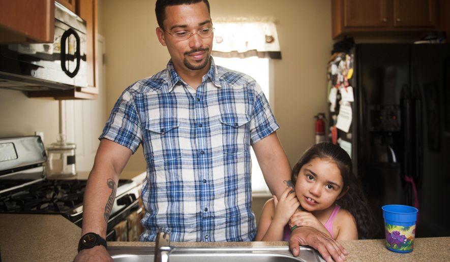 In this July 31, 2014 photo, Tatyana "Tuffy" Rivera, 7, holds on to her father, Ricardo, in the kitchen of their Camden County, N.J. home. Diagnosed at 10 months with a severe form of epilepsy called Lennox-Gastaut syndrome, Tatyana suffered up to 300 seizures a day, but gets significant relief since her father started treating with marijuana-infused coconut oil he cooks up for her on the stove. (AP Photo/Courier-Post, Jodi Samsel)