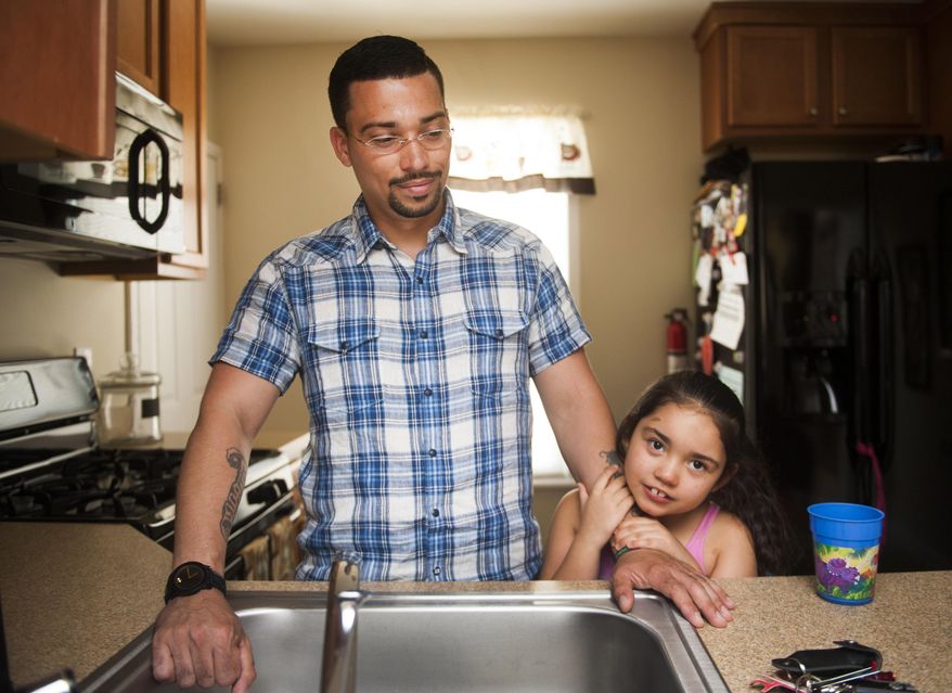 In this July 31, 2014 photo, Tatyana "Tuffy" Rivera, 7, holds on to her father, Ricardo, in the kitchen of their Camden County, N.J. home. Diagnosed at 10 months with a severe form of epilepsy called Lennox-Gastaut syndrome, Tatyana suffered up to 300 seizures a day, but gets significant relief since her father started treating with marijuana-infused coconut oil he cooks up for her on the stove. (AP Photo/Courier-Post, Jodi Samsel)