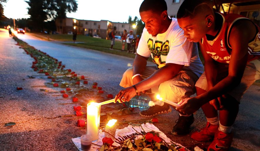 Mourners light candles at a memorial on Canfield Drive in Ferguson, Missouri, where unarmed Michael Brown was fatally shot by a police officer.
In this photo taken on Thursday, Aug. 21, 2014, Theo Murphy, left, of Florissant, Mo., and his brother Jordan Marshall, 11, light candles at a memorial on Canfield Drive in Ferguson, Mo., where where unarmed Michael Brown was fatally shot by Ferguson Police Officer Darren Wilson. A small group of people, who preferred to remain anonymous,laid roses along the middle of the road that stretched about 60 yards. (AP Photo/St. Louis Post-Dispatch, Christian Gooden)  EDWARDSVILLE INTELLIGENCER OUT; THE ALTON TELEGRAPH OUT (Associated Press)