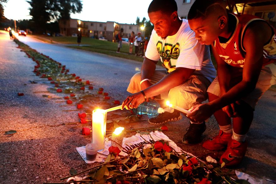 Mourners light candles at a memorial on Canfield Drive in Ferguson, Missouri, where unarmed Michael Brown was fatally shot by a police officer.
In this photo taken on Thursday, Aug. 21, 2014, Theo Murphy, left, of Florissant, Mo., and his brother Jordan Marshall, 11, light candles at a memorial on Canfield Drive in Ferguson, Mo., where where unarmed Michael Brown was fatally shot by Ferguson Police Officer Darren Wilson. A small group of people, who preferred to remain anonymous,laid roses along the middle of the road that stretched about 60 yards. (AP Photo/St. Louis Post-Dispatch, Christian Gooden)  EDWARDSVILLE INTELLIGENCER OUT; THE ALTON TELEGRAPH OUT (Associated Press)