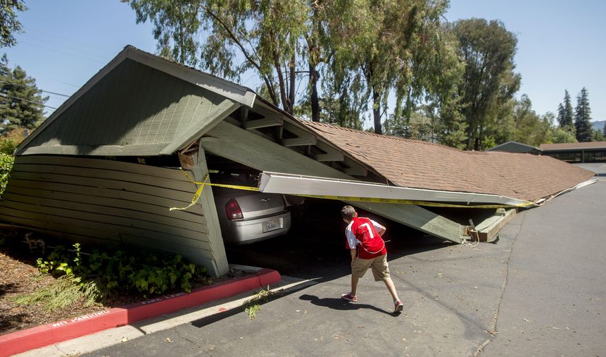 A boy examines cars trapped beneath a collapsed carport at Charter Oaks apartments in Napa, Calif., following an earthquake Sunday, Aug. 24, 2014. More than fifteen vehicles were trapped or crushed as multiple carports collapsed at the complex during a large earthquake. (AP Photo/Noah Berger)