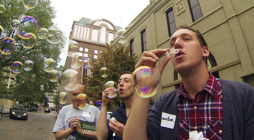 Brandon Herr, right, and Matt Antonczyk blow bubbles at a rally Monday, Aug. 25, 2014 in Milwaukee as gay couples and their supporters board a bus for a trip to Chicago for a key hearing in the fight against same-sex marriage bans. On Tuesday the 7th Circuit Court of Appeals in Chicago will hear oral arguments in a combined appeal from Wisconsin and Indiana where same-sex marriage were ruled unconstitutional in June. (AP Photo/Carrie Antlfinger)