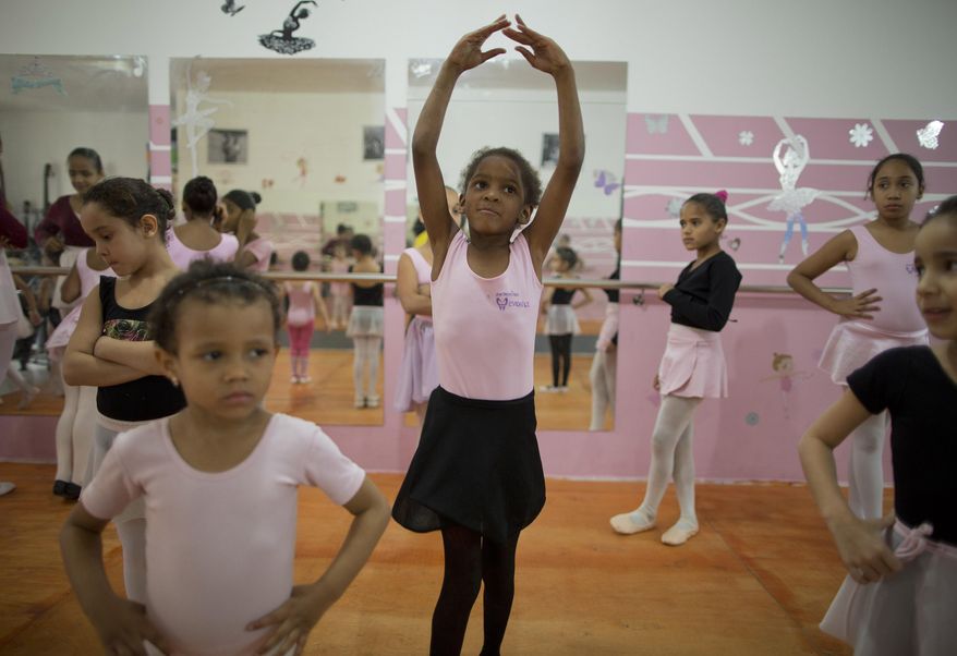 In this Aug. 8, 2014 photo, girls participate in a ballet class at the House of Dreams dance studio in Crackland, one of the roughest neighborhoods in downtown Sao Paulo, Brazil. Growing up amid drug dealers and addicts, some girls have yet to learn how to read. Yet they are learning the graceful art of ballet courtesy of a local church group that also offers them food, counseling and Bible studies. (AP Photo/Andre Penner)