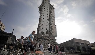 Palestinians inspect the damage to the Italian Complex following several late night Israeli airstrikes in Gaza City, Tuesday, Aug. 26, 2014. Israel bombed two Gaza City high-rises with dozens of homes and shops Tuesday, collapsing the 15-story Basha Tower and severely damaging the Italian Complex in a further escalation in seven weeks of cross-border fighting with Hamas. (AP Photo/Khalil Hamra)