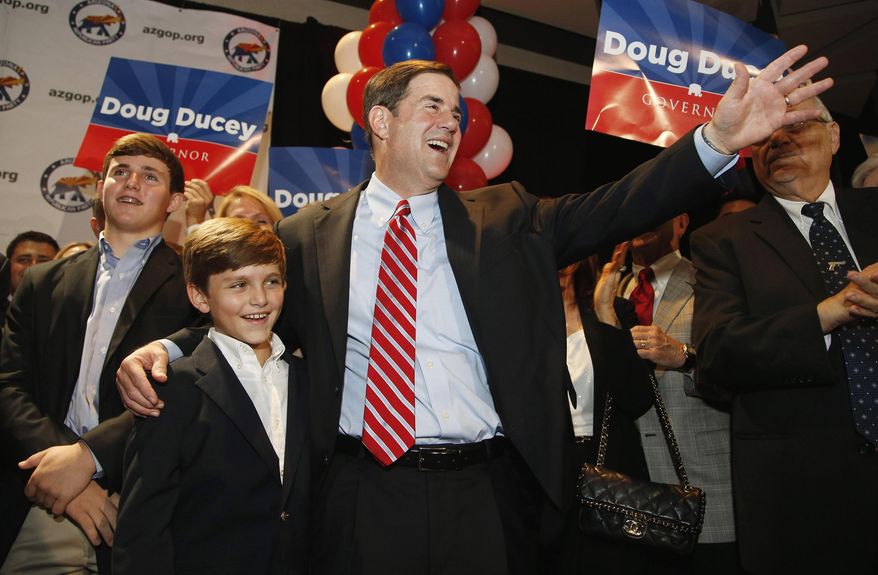 State treasurer and former CEO Doug Ducey, right, hugs his son Sam Ducey, with other son Joe Ducey, left, joining them as they all smile as the candidate arrives to claim victory on winning the Republican primary for Arizona governor Tuesday, Aug. 26, 2014, in Phoenix. Ducey defeated five other Republican candidates and will face Democrat Fred DuVal, who was unopposed in the primary, in November. (AP Photo/Ross D. Franklin)
