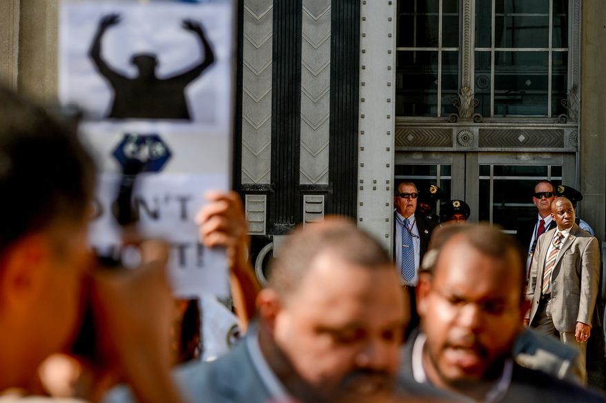 Justice Department security watch from the Connsititution Ave. entrance as activists rally outside the Justice Department to call on the Attorney General to "help secure justice for Michael Brown and the people of Ferguson, Missouri, as well as an overhaul of US law enforcement tactics in order to stop police brutality and the militarization of police forces", Washington, D.C., Wednesday, August 27, 2014. (Andrew Harnik/The Washington Times)